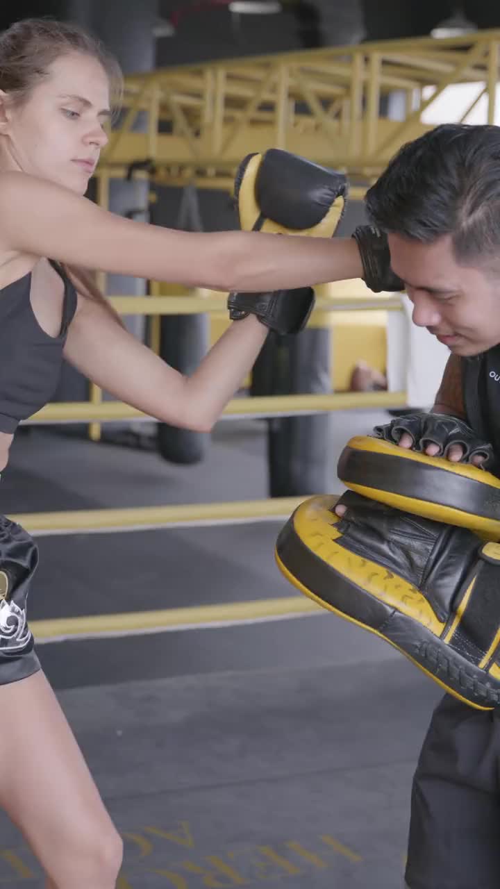 Student working on Muay Thai pad technique with a trainer